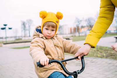 Grandmother teaches small child to ride bike for the first time in city spring