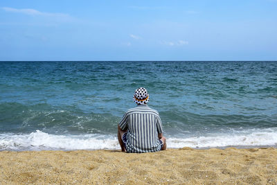 Man sits on the seashore and relaxes. looks into the boundless blue distance. copy space.