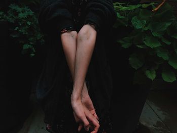 Low section of woman sitting by plants