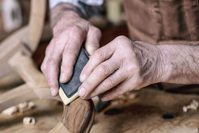 Close-up of carpenter polishing wood in workshop