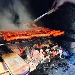 Cropped hand grilling sausages on barbecue