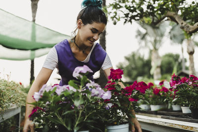 Female owner carrying flowering plants at nursery