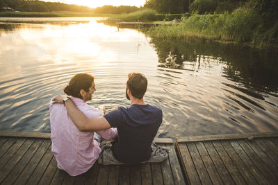 Rear view of couple sitting by lake