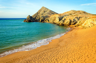 Scenic view of shore and sea against blue sky