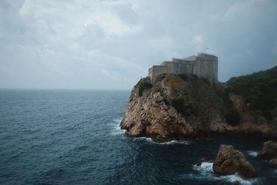 Scenic view of castle at sea against cloudy sky