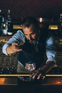 Bartender preparing cocktail at counter in bar