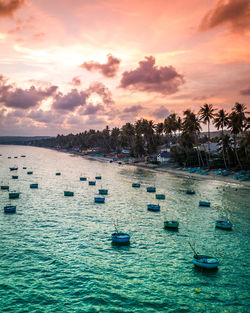 Sailboats in sea against sky during sunset