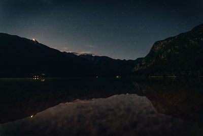 Scenic view of lake and mountains against sky at night