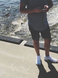 Low section of man standing on beach