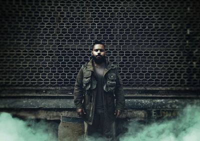 Portrait of young man standing against wall