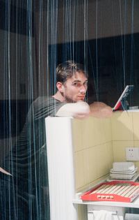 Portrait of young man looking through window