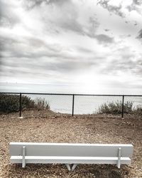 Empty bench on land against sea