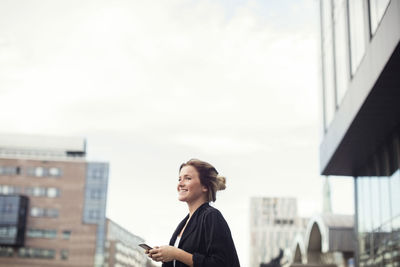 Side view of a woman looking at city buildings