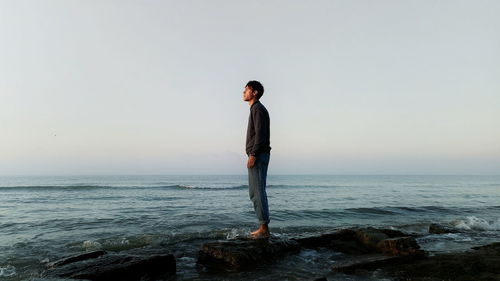 Woman standing on beach against clear sky