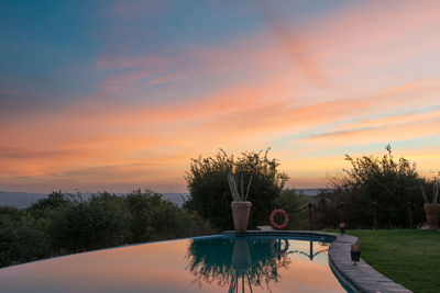 Scenic view of swimming pool by lake against sky during sunset