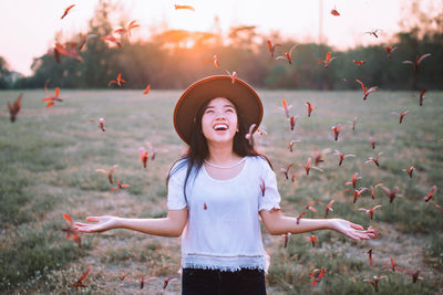 Happy woman throwing flowers during sunset