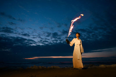 Man standing at beach against sky during sunset