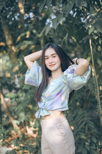 Portrait of a smiling girl standing against tree