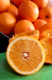 Close-up of orange fruit in front of a bowl of oranges making juice