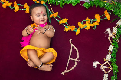 Cute indian boy dresses as lord rama with bow and flowers from top angle