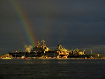 Illuminated commercial dock by sea against sky