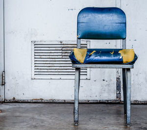 Empty chair on sidewalk against building