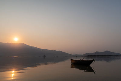 Boat on lake against sky during sunset