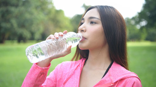 Portrait of woman drinking water from bottle