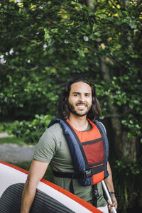 Portrait of smiling man holding paddleboard