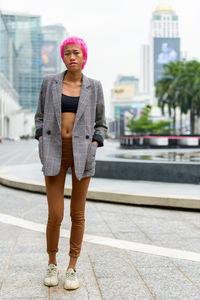 Full length portrait of young woman standing outdoors