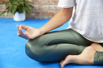 Low section of woman doing yoga at poolside