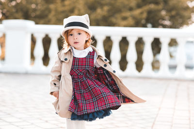 Portrait of cute girl standing against baluster