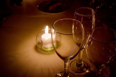 Wineglasses by illuminated tea light candle on table