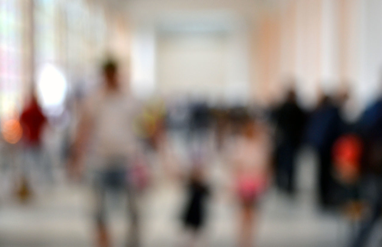 DEFOCUSED IMAGE OF PEOPLE WALKING IN FRONT OF WALL