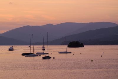 Silhouette sailboats in sea against sky during sunset