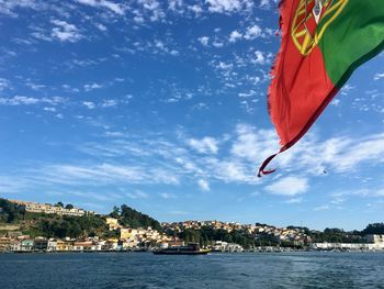 Scenic view of a portuguese flag at the back of a boat with blue sky and a small village in the back