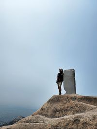 Rear view of man walking on mountain against clear sky