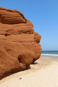 Rock formation at sea shore against sky