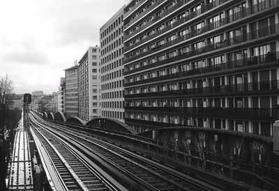 Railroad tracks by buildings in city against sky