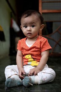 Portrait of cute baby girl sitting at home