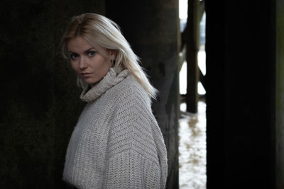 Portrait of young woman standing against window
