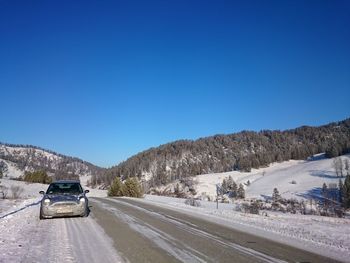 Car on road against clear blue sky