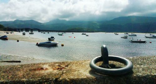 Boats in sea against cloudy sky