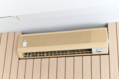 Air conditioner on brown wall room interior background.