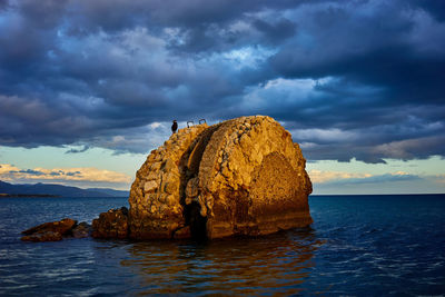 Rock formation by sea against sky