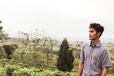 Young man standing on land against sky