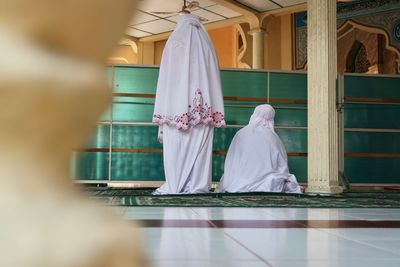 Rear view of women wearing traditional dress praying in mosque