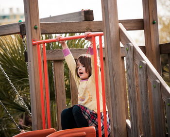 Full length of boy sitting on slide at playground
