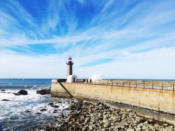 Lighthouse by sea against blue sky