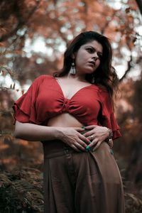 Young woman standing against trees in forest